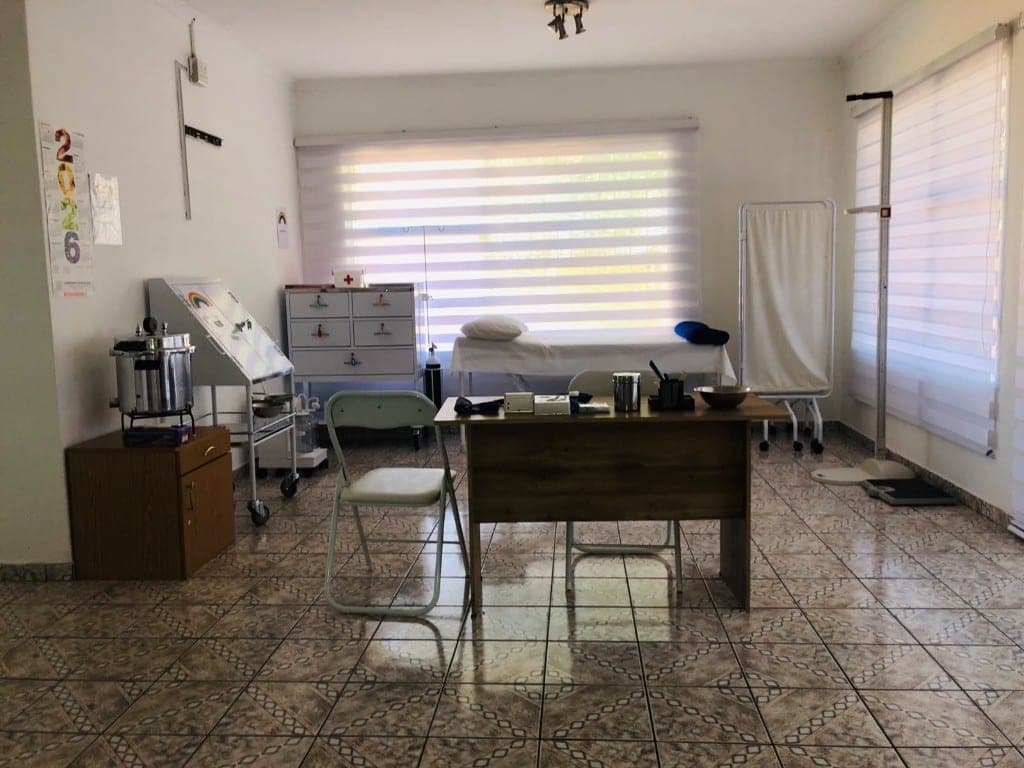 Examination room with bed, privacy screen, and clinical supplies at Elshaddai Health Care Centre